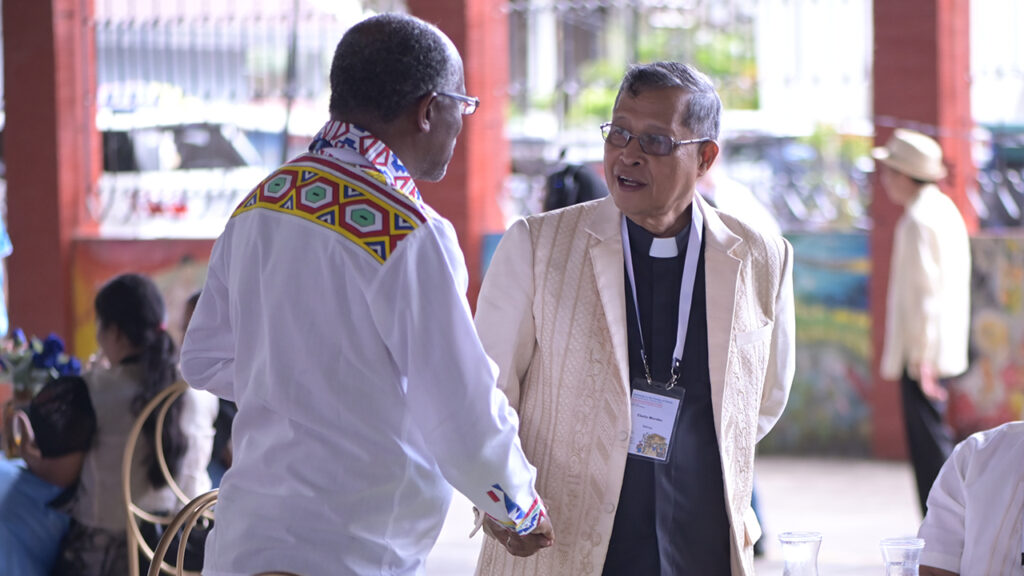 Sindah Ngulube, left, a bishop from Brethren in Christ Church of Zimbabwe, greets IMC President Eladio Mondez. — RG Photography/MWC