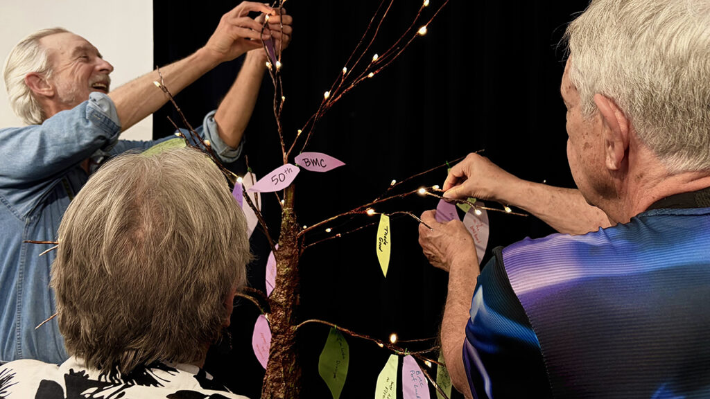 Jim Lichti of San Francisco, Leann Toews of Goessel, Kan., and Keith Gerber of Bloomington, Ind., add memories to a tree during a “sacred space” ritual. — Xaris A. Martínez/BMC