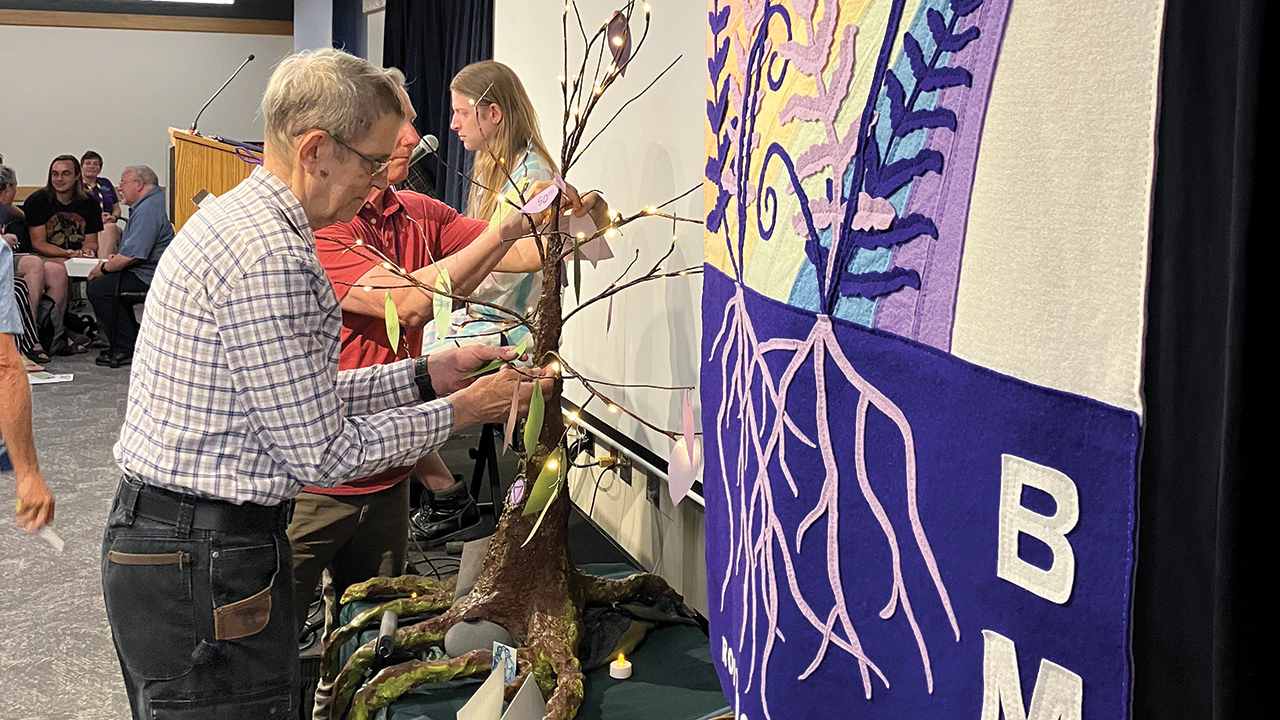 John Linscheid, who accepted an apology in 2025 from Western District Confer­ence of Mennonite Church USA for rescinding his ministry credential in 1984, adds a memory to a tree during a “sacred space” ritual at the BMC anniversary celebration. — Paul Schrag/AW