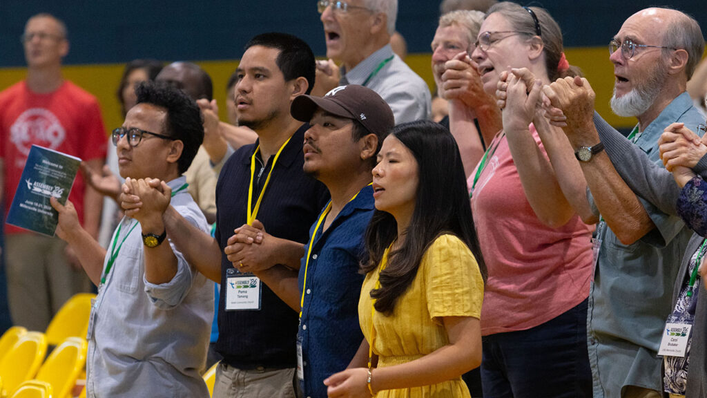 Worshipers join hands while singing during a worship service. — Jonathan Charles for AW