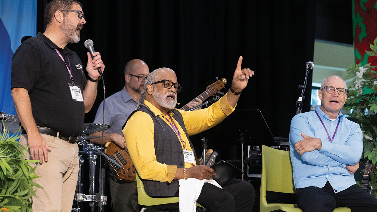 Philadelphia District Bishop Alvin Motley sings while preaching during the LMC assembly June 20 in Millersville, Pa., as Martindale District Bishop Daryl L. Weaver, left, and Executive Bishop Team member Keith Blank join in. — Jonathan Charles for AW