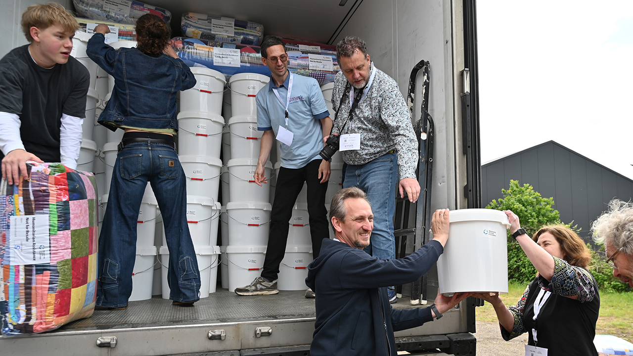 Max and Anya, Mennonite Brethren church leaders in Ukraine, hand a Mennonite Central Committee relief kit to other volunteers loading a truck with supplies destined for Ukraine. — Scott Stoner-Eby/MCC