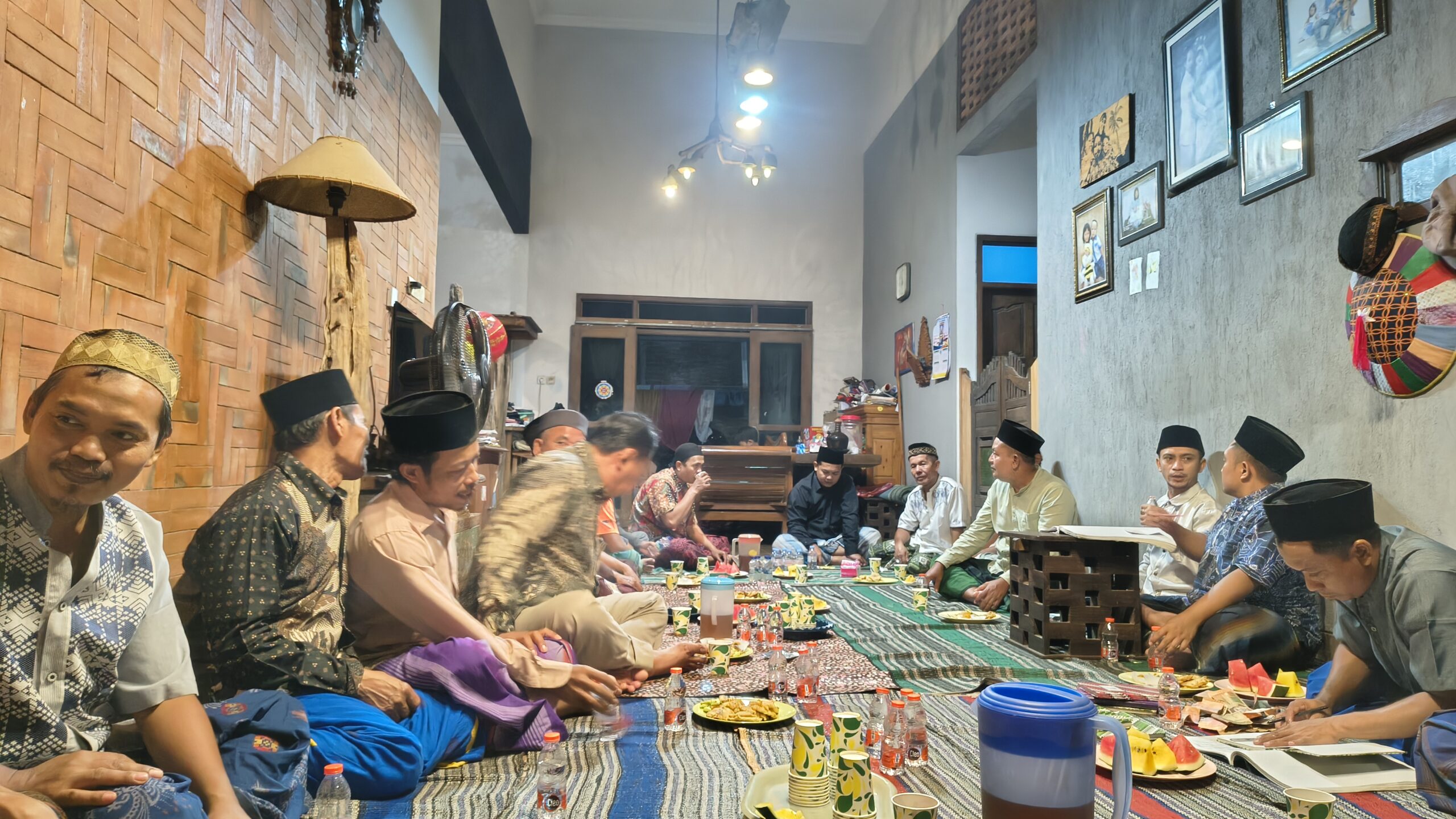 Neighbors gathered for neighborhood meeting, sitting cross-legged in sarongs and traditional peci caps, sharing snacks and conversation before the meeting began. This photo shows those inside the house; others were gathered on the front porch. Photo by Danang Kristiawan