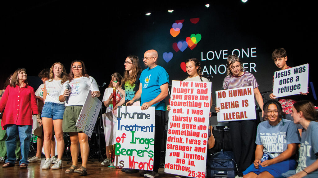 Members of Roanoke Mennonite Church in Eureka, Ill., dramatize a scripture reading with signs of support for immigrants at the Mennonite Church USA convention in July 2025 in Greensboro, N.C. — Juan Moya/AW