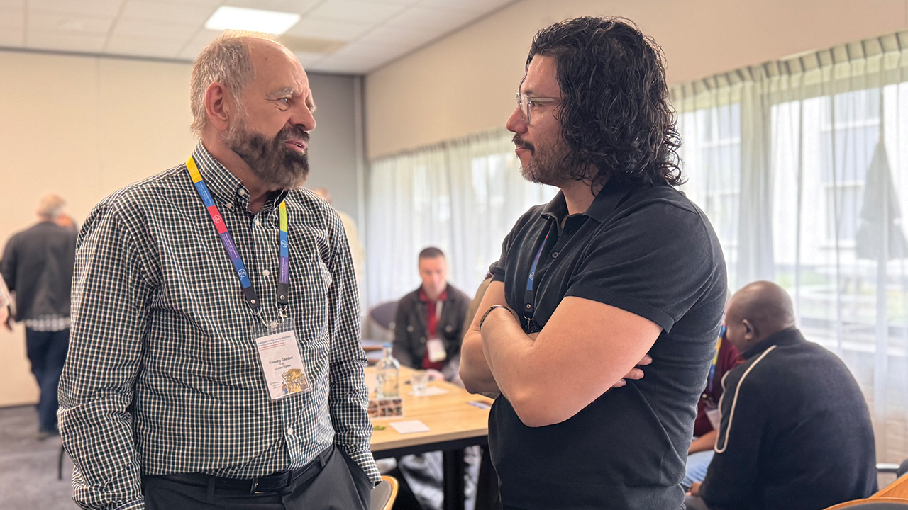 Tim Geddert, left, talks with Andres Pacheco Lozano, chair of the Mennonite World Conference Peace Commission, at a gathering of MWC’s commissions in the Netherlands in May. — MWC