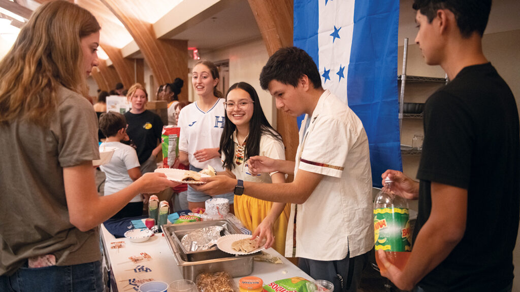 Phoebe Turcios, Ana Espinoza, Pablo Turcios Casco and Olvin Duron serve Honduran fare to Dara Ness, left, at Hesston College’s Cultures Fair in the fall of 2023. — Larry Bartel/Hesston College