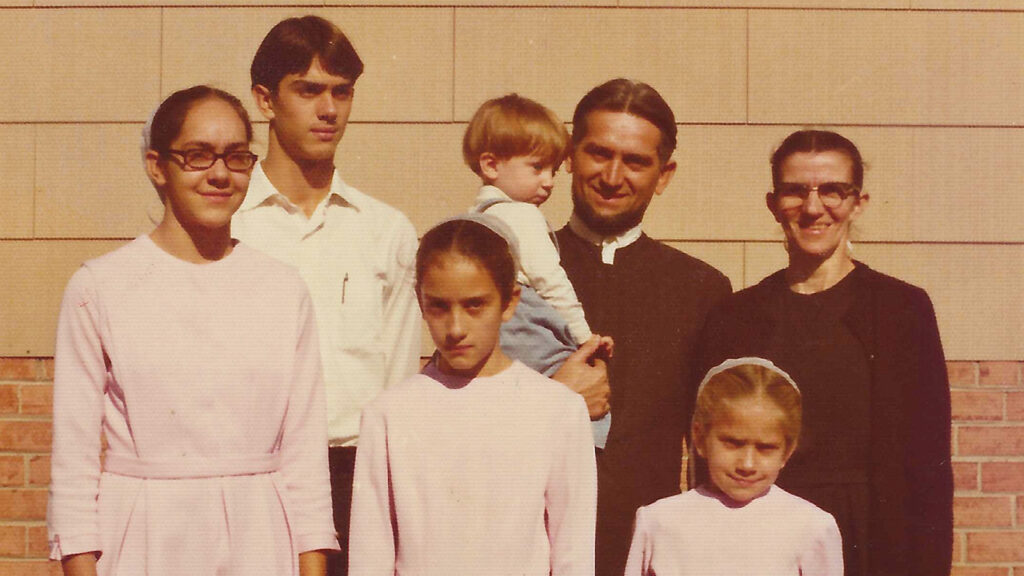 The Lapp family poses for a 1975 photo in front of one of the Kenilworth-area houses owned by the church. The toddler held by Elmer Lapp is this article’s author. — Courtesy of Joe Lapp