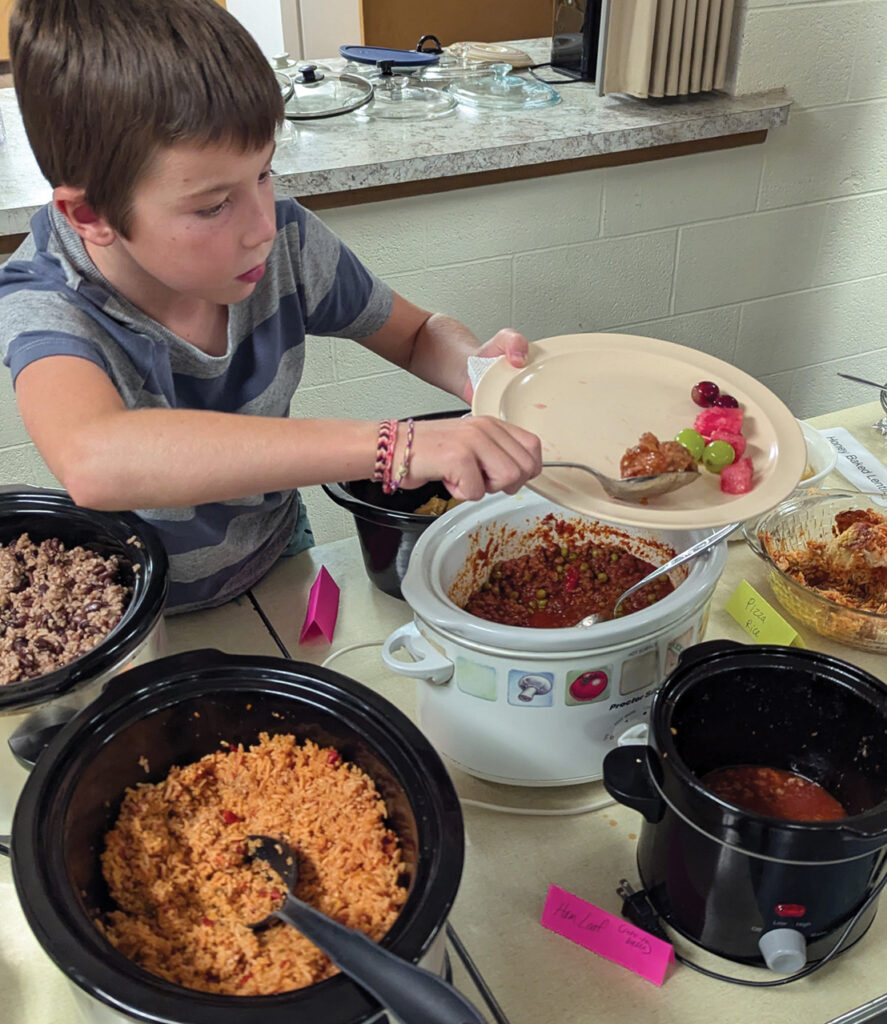 Milo Klingenberg fills his plate Aug. 2 at Zion Mennonite Church in Elbing, Kan. — Tim Huber/AW
