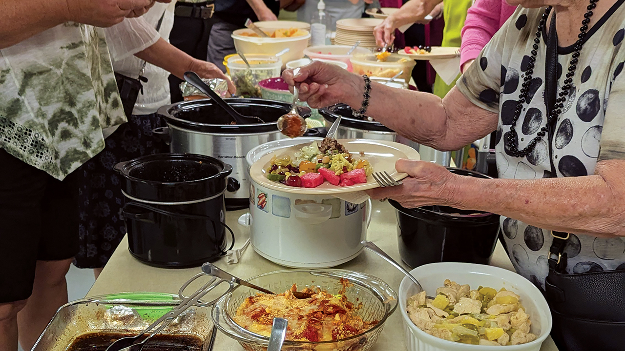 Congregants sample the choices at a potluck celebrating the 50th anniversary of Doris Janzen Longacre’s More-with-Less Cookbook at Zion Mennonite Church in Elbing, Kan., on Aug. 2. — Tim Huber/AW